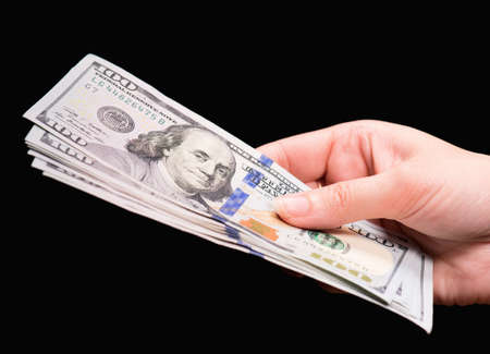 Close up of female hand holding money - US dollar banknotes against dark backgroundの写真素材