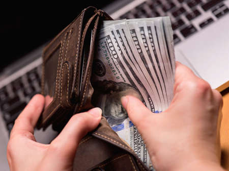 Close up of female hands counting US dollar banknotes at the table in front a laptop computer. Woman accountant with money and notebook.の写真素材