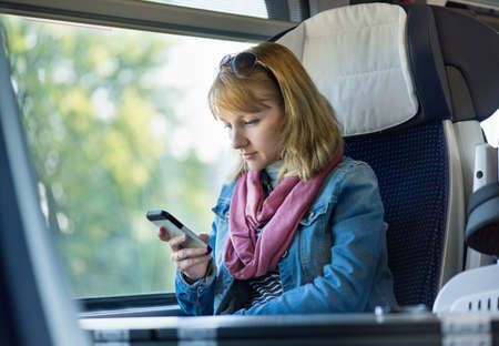 Beautiful young woman traveler in a train or bus, making phone call.の写真素材