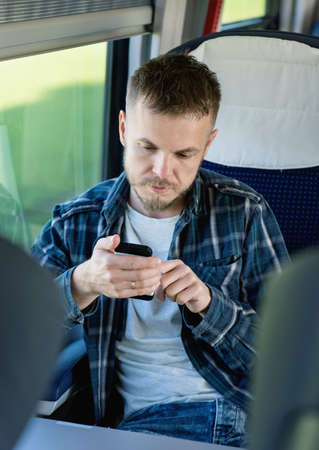 Young man traveler in a train or bus with mobile phoneの写真素材