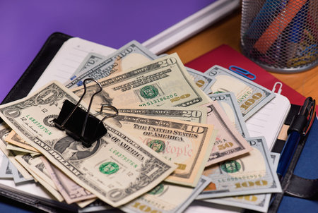 Notepad with US dollar banknotes and pen on table