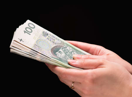 Close up of female hand holding Polish money banknotes against dark backgroundの写真素材