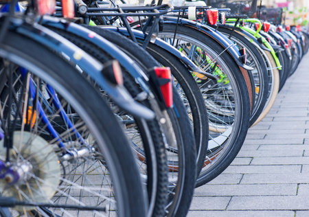 Group of bicycles in the row on sidewalk. Selective focus. Parking for bikes in big European city. Close up of wheel.の写真素材