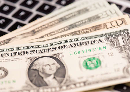Workplace with money and notebook - US dollar banknotes on keyboard of laptop computer.の写真素材