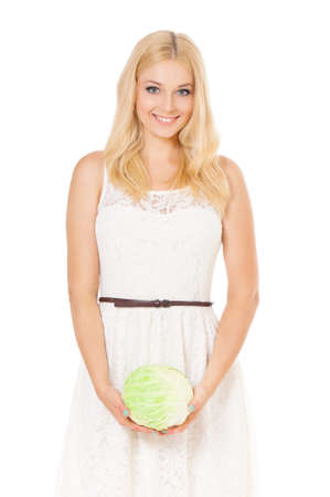 Half-length portrait of beautiful woman holding fresh cabbage and looking at us. Smiling young housewife with green head of cabbage. Studio shot isolated on white background. Healthy eating concept.の写真素材