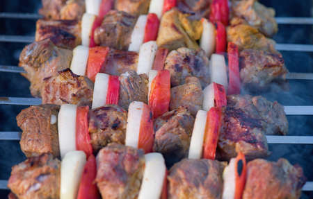 Barbecue with delicious grilled meat on grill. Pork meat pieces being fried on a charcoal grill.の写真素材