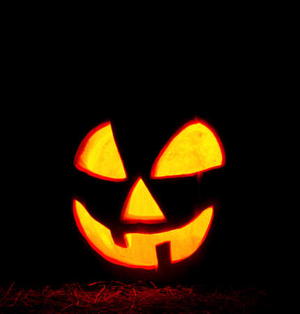 Scary Halloween pumpkin on black background. Glowing pumpkin with candle inside. Decorations for Halloween.の写真素材