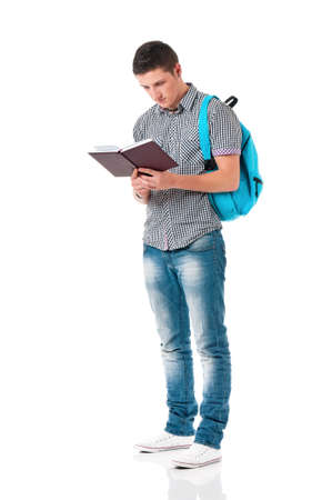 Handsome teen boy with backpack and notepad, isolated on white background. Full length portrait of a young man reading book. Adult male student with school bag carrying text books.の写真素材