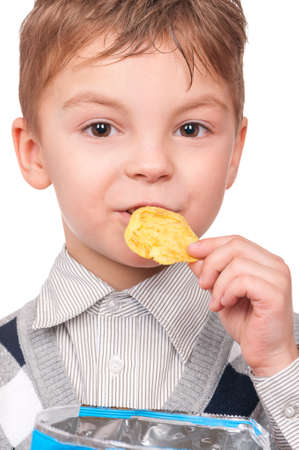 Portrait of cheerful little boy with packet of potato chips. Close-up of child eating fast food, isolated on white background.の写真素材