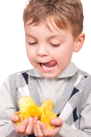 Portrait of cheerful little boy with packet of potato chips. Close-up of child eating fast food, isolated on white background.の写真素材