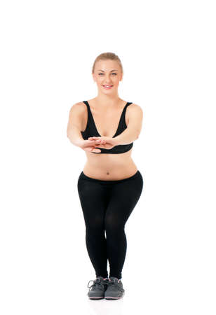 Beautiful fitness woman posing in studio - showing how to keep fit doing warming up exercises. Young sportswoman, isolated on white background.の写真素材
