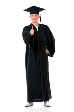 Handsome graduate guy student in mantle showing thumb sign, isolated on white backgroundの写真素材