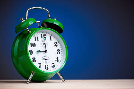 Big green alarm clock on dark blue backgroundの写真素材