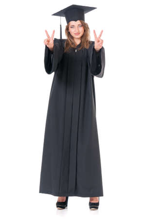 Beautiful graduate girl student in mantle showing victory sign, isolated on white backgroundの写真素材