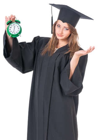 Young graduate girl student in mantle with alarm clock, isolated on white backgroundの写真素材