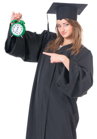 Young graduate girl student in mantle with alarm clock, isolated on white backgroundの写真素材