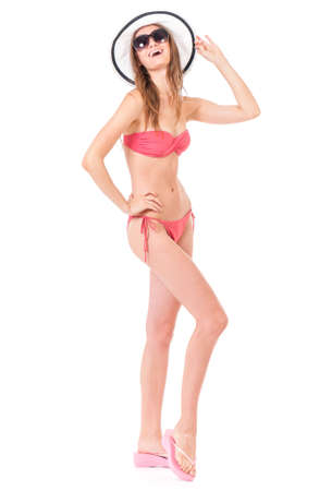 Sexy young woman posing in a pink bikini, summer hat and sunglasses, isolated on white backgroundの写真素材