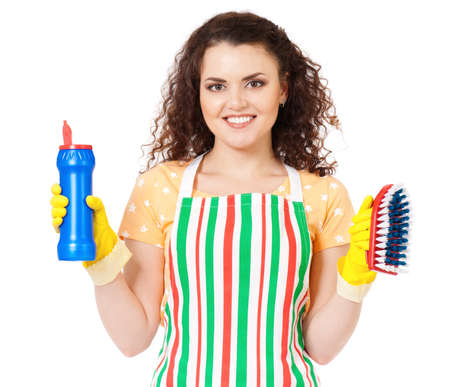 Smiling young woman holding bottle of chemistry for cleaning house. Cleaning concept. Beautiful happy girl with cleaning tools and products on white background. Housekeeper isolated portrait.の写真素材