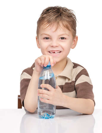 Portrait of cheerful little boy with plastic bottle of water. Cute smiling child drinks water, isolated on white background.の写真素材