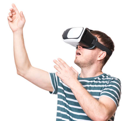 Amazed man wearing virtual reality goggles watching movies or playing video games, isolated on white background. Surprised male in VR glasses. People experiencing 3D technology.の写真素材