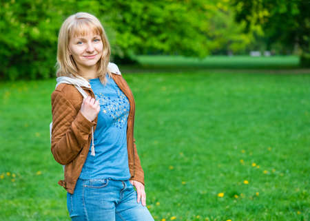 Portrait of attractive smiling caucasian young woman in spring park looking at camera - outdoors.の写真素材