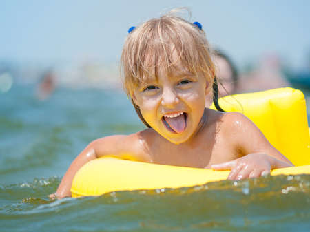 Portrait of little smiling girl with inflatable rubber circle in the sea in sunny day. Summer vacations concept.の写真素材