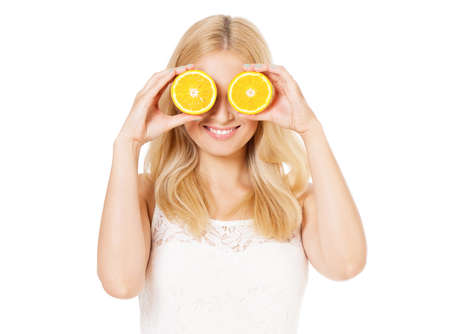Portrait of happy woman with half orange. Beautiful girl holds piece of a cut orange in her hands and laughs, isolated on white background. Healthy lifestyle concept.の写真素材