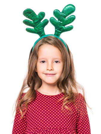 Portrait of smiling little girl with funny Christmas antlers of a deer. Holiday concept - happy cute child looking at camera, isolated on white background.の写真素材