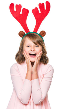 Portrait of smiling little girl with Christmas antlers of a deer. Holiday Christmas concept - happy cute child isolated on white background.の写真素材
