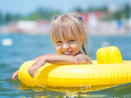 Portrait of little smiling girl with inflatable rubber circle in the sea in sunny day. Summer vacations concept.の写真素材
