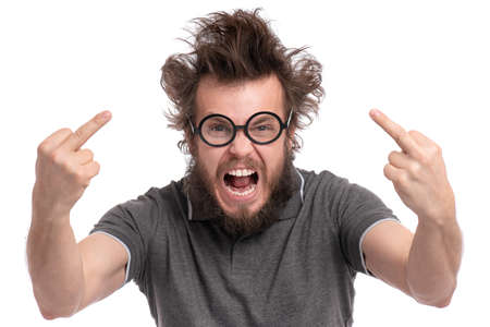 Crazy bearded Man with funny Haircut  in eye Glasses, Screaming and showing the Middle Fingers, isolated on white background. Portrait of Angry Man looking at camera in anger - studio shot.の写真素材
