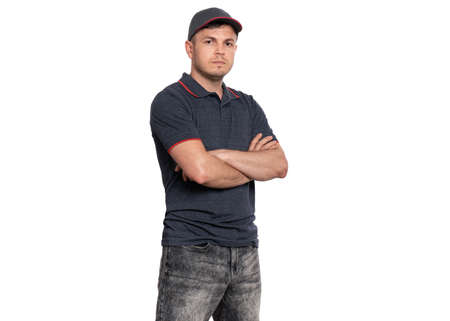 Delivery man in gray t-shirt and cap. Studio portrait of caucasian handsome guy with arms folded and looking on camera. Courier isolated on white background.の写真素材