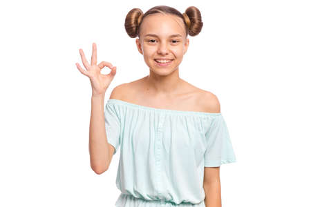 Portrait of teen girl making Ok Gesture, isolated on white background. Beautiful caucasian young teenager smiling and giving OK sign. Happy cute child showing okay.の写真素材