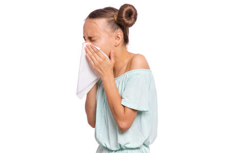 Portrait of unhealthy sick teen girl with napkin close her nose from allergy or rhinitis. Unhappy ill child suffering from running nose and sneezing and blow her nose isolated on white background.の写真素材