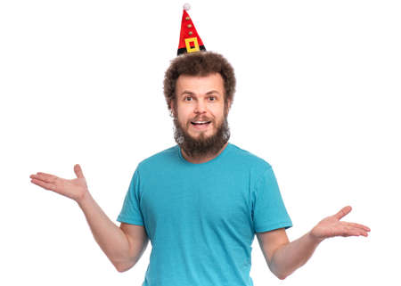 Crazy bearded Man with funny Curly Hair in little Christmas hat smiling and looking at camera. Happy guy in Santa hat, isolated on white background. Holidays concept.の写真素材