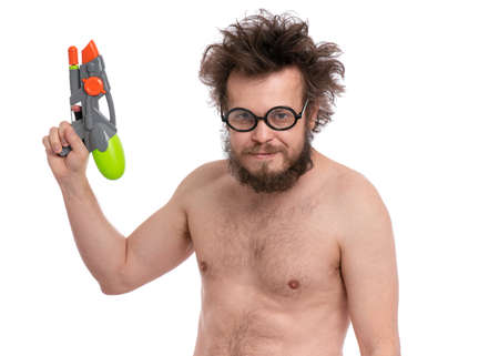 Crazy bearded Man with funny Haircut in eyeglasses, ready for fun at sunny beach. Happy and silly tourist, isolated on white background. Cheerful naked man holding Water Gun.の写真素材