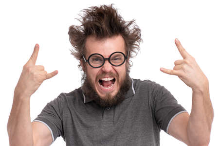 Crazy Bearded happy Man with funny Haircut in Eyeglasses making rock and roll gesture. Cheerful and silly guy, isolated on white background.の写真素材