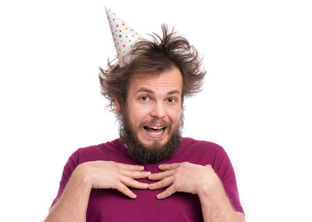 Crazy bearded Man with funny Haircut in birthday cap, isolated on white background. Happy guy smiling and looking at camera. Holidays, Emotions and Signs concept.の写真素材