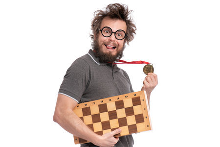 Crazy bearded Man with funny Haircut in eyeglasses holding gold Medal and Chess board. Happy winner,...