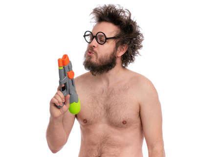 Crazy bearded Man with funny Haircut in eyeglasses, ready for fun at sunny beach. Happy and silly tourist, isolated on white background. Cheerful naked man holding Water Gun.の写真素材