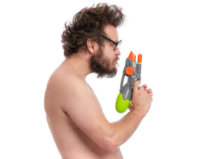 Crazy bearded Man with funny Haircut in eye Glasses, ready for fun at sunny beach. Happy and silly tourist, isolated on white background. Cheerful naked man holding Water Gun.の写真素材