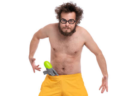 Crazy bearded Man with funny Haircut in eye Glasses, ready for fun at sunny beach. Happy and silly tourist, isolated on white background. Cheerful naked man holding Water Gun.の写真素材