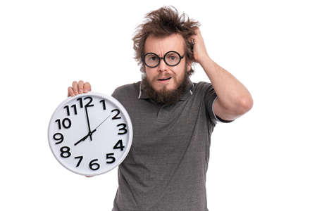Crazy bearded Man with funny Haircut in eye Glasses holding Big Clock, isolated on white background. Time concept.の写真素材
