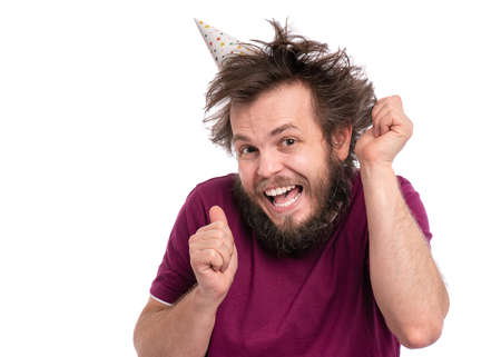 Crazy bearded Man with funny Haircut in birthday cap, isolated on white background. Happy guy smiling and dancing. Holidays, Emotions and Signs concept.の写真素材