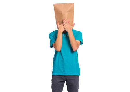 Portrait of teen boy with paper bag over head, covering mouth with hands, isolated on white background. Child posing at studio. Speak no evil concept.の写真素材
