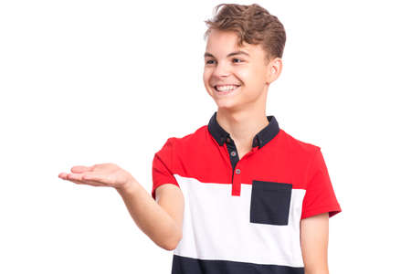 Portrait of cute smiling teen boy holding copy space on his palm. Happy teenager lookind away, isolated over white background. Child holds and show something on palm.の写真素材