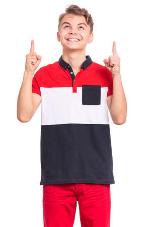Portrait of surprised teen boy pointing fingers up at copyspace, isolated on white background. Teenager pointing finger at something. Cute amazed child looking away.の写真素材