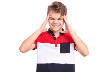 Portrait of teen boy touching his head suffering headache looking tired and sad. Unhappy beautiful caucasian young teenager suffering from headache, isolated on white background.の写真素材