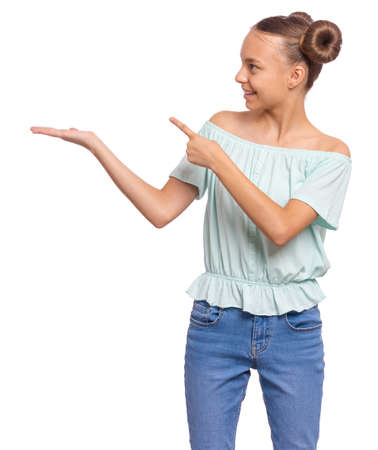 Portrait of teen girl pointing finger away at copyspace, isolated on white background. Beautiful caucasian young teenager smiling and attracted by attention pointing finger at something. Happy child.の写真素材