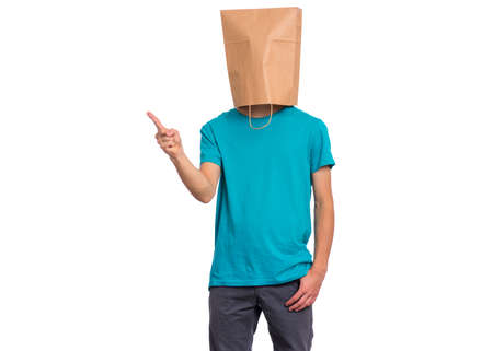 Portrait of teen boy with paper bag over head pointing hands away at copyspace, isolated on white background. Child pointing finger at something.の写真素材